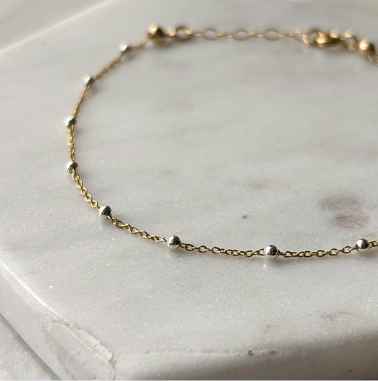 gold and silver chain bracelet on a marble background