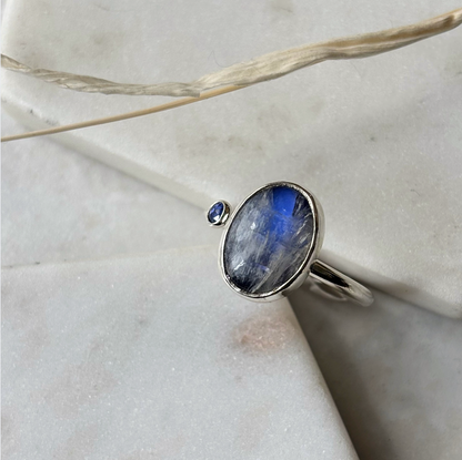 Silver ring with a blue gemstone on a marble surface
