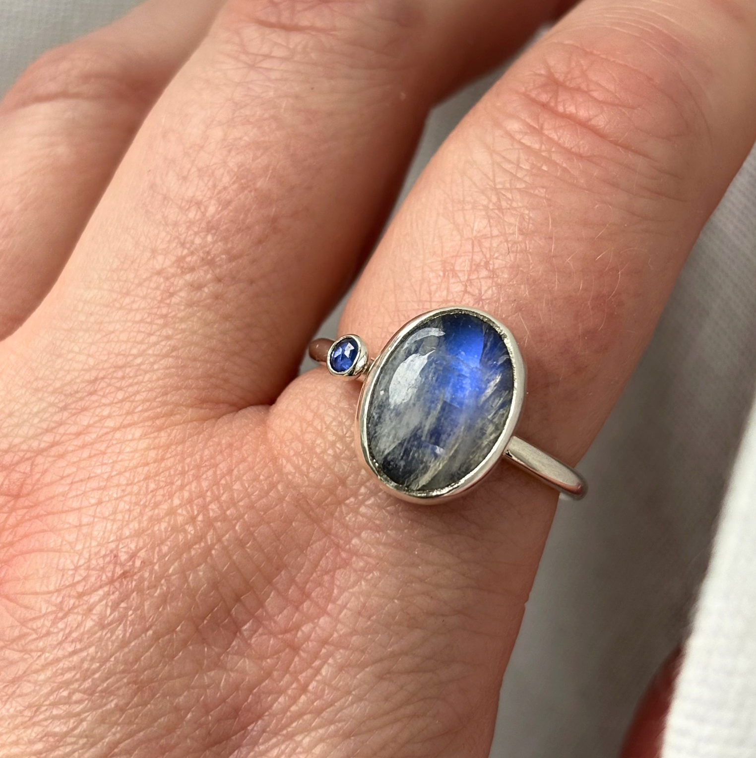 silver ring with a blue gemstone on a finger