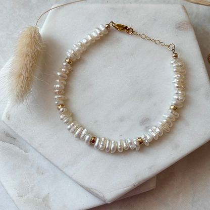 Pearl bracelet with gold accents on a marble surface
