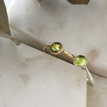 Two larger peridot rings in silver and gold fill on a marble background.