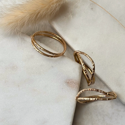 Gold textured rings on a marble surface with a fluffy object in the corner.