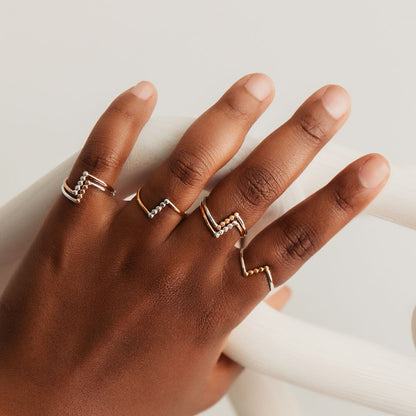 A person wearing three rings, with a gold band and silver accents.