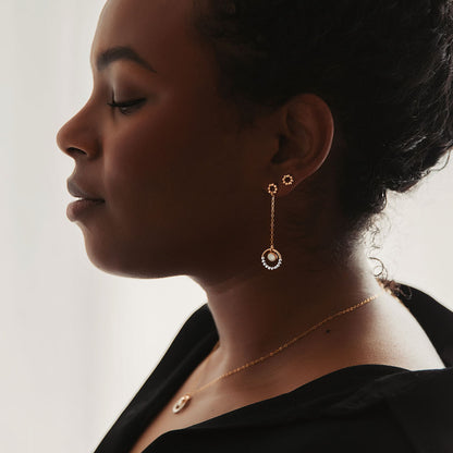 A mixed metal opal dangle earring on a person.