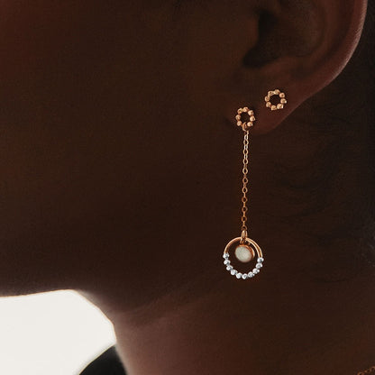 A mixed metal opal dangle earring on a person.