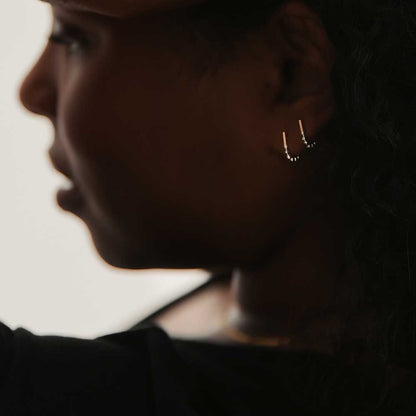A set of two J-hoop earrings made of sterling silver with hand-textured orbs, worn by a model.