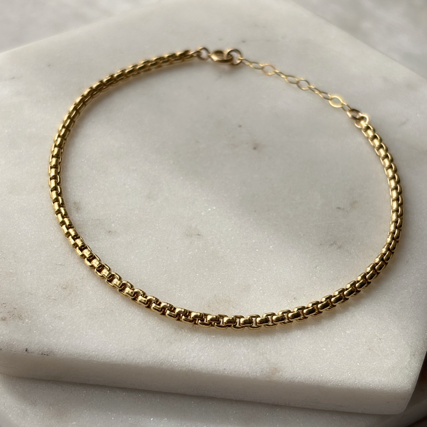 Gold chain bracelet on a marble surface