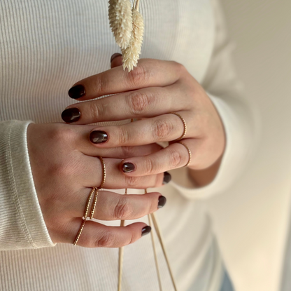 A person wearing multiple gold stacking rings with texture.