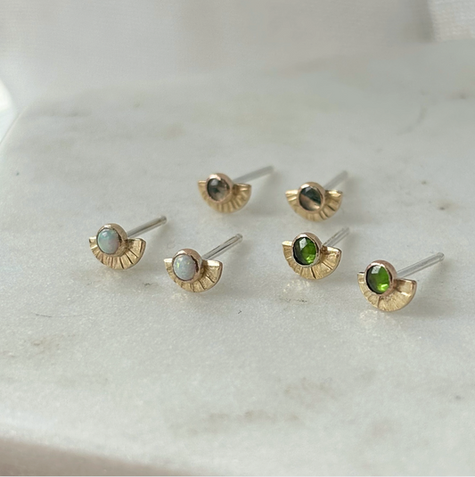 Set of gold and gemstone stud earrings on a marble surface