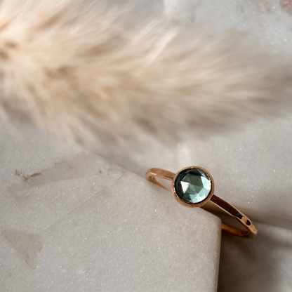 Gold ring with a swiss blue topaz faceted gemstone on a textured surface