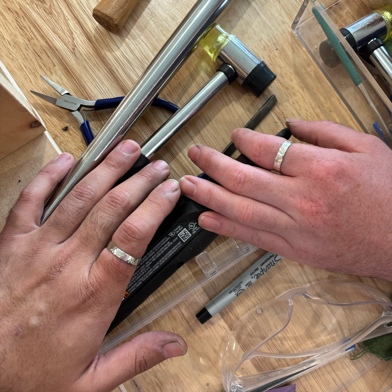 Close-up of hands working on a cylindrical object with tools on a wooden surface