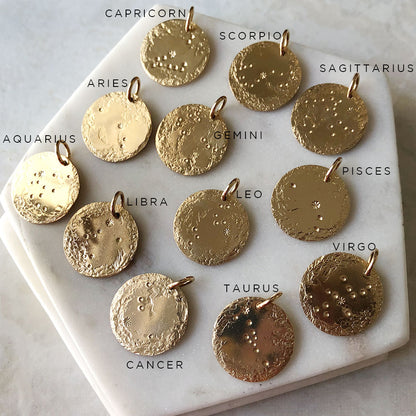 twelve zodiac pendant charms on a marble background.