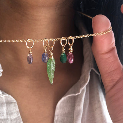 A person holding multiple gemstone charms on a chain.
