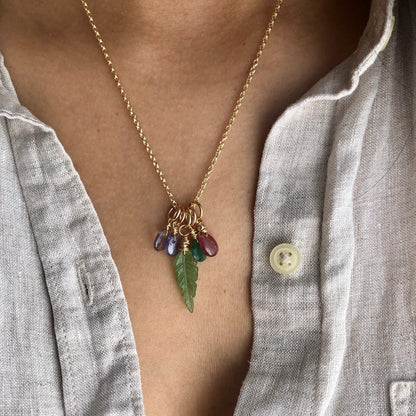A person wearing multiple gemstone charms on a chain.