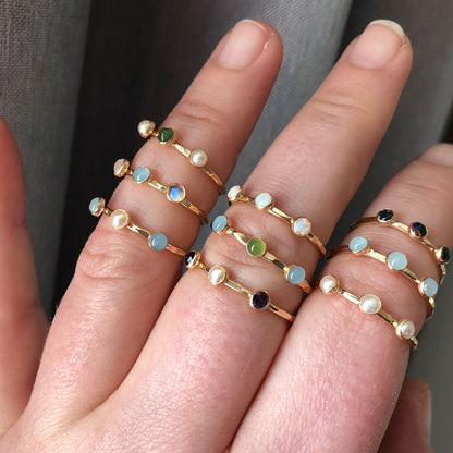 Multi gemstone rings in gold on a hand.