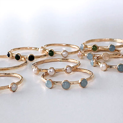 Multi gemstone rings in gold on a hand.